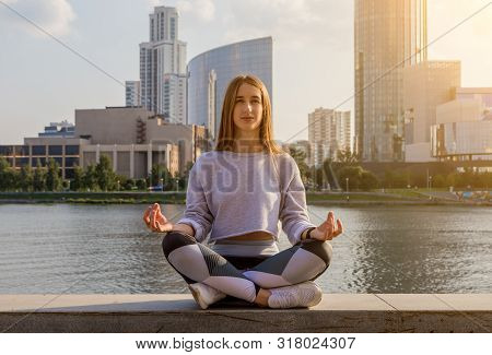 Beautiful Young Woman Practices Yoga Asana Padangustha Padma Utkatasana - Half Lotus Toe Balance Pos
