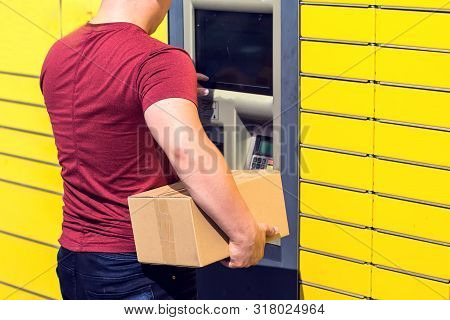Man Client Using Automated Self-service Post Terminal Machine Or Locker To Depisit A Parcel For Stor