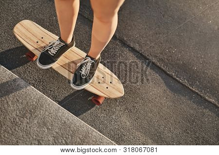 Upper-angle Cropped Shot Caucasian Woman Hands In Sneakers Standing On Wooden Penny Board, Perform K