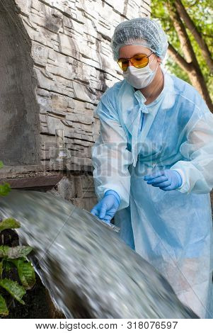 Female Sanitary Inspector Or Epidemiologist Takes A Sample Of Water From Urban Wastewater