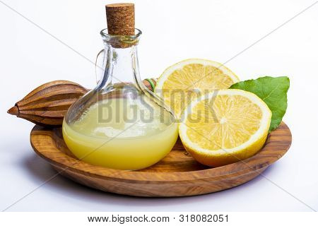 Fresh Lemon Juice Made From Ripe Yellow Sicilian Lemons Used For Cooking In Glass Bottle On Olive Wo