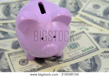 A Closeup Of A Piggy Bank Overtop Of An Abundance Of American Money.