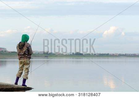 Yakut Girl-tourist Angler Fishing Spinning Reel Standing In Boots On The Shore In The Background Of 