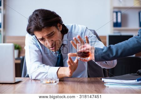 Male employee drinking alcohol and smoking cigarettes at workpla