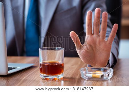 Male employee drinking alcohol and smoking cigarettes at workpla