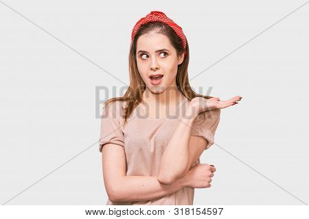 Studio Shot Of Amazed Beautiful Young Woman Looking At One Side With Surprised Expression And Wide O