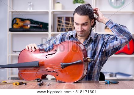 Young handsome repairman repairing cello