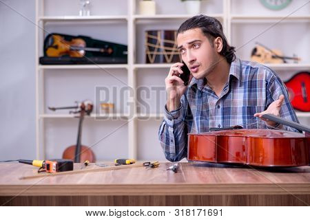 Young handsome repairman repairing cello