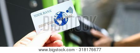 Male Hand Hold White Plastic Credit Card Aganist Gasoline Station. Wireless Payment Terminal Concept
