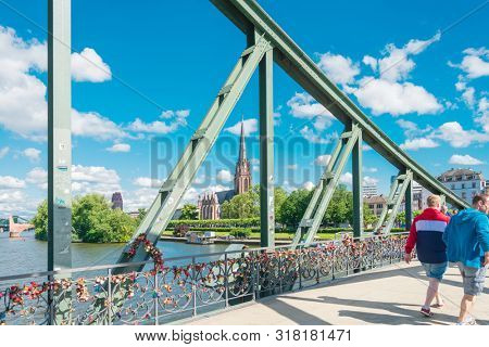 Frankfurt, Germany - June 12, 2019: River view of The Eiserner Steg.The Eiserner Steg is a pedestrian bridge in Frankfurt am Main built in 1868. City skyline in Frankfurt, Germany.