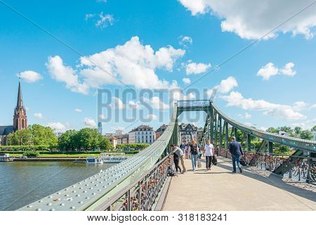 Frankfurt, Germany - June 12, 2019: River view of The Eiserner Steg.The Eiserner Steg is a pedestrian bridge in Frankfurt am Main built in 1868. City skyline in Frankfurt, Germany.