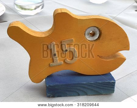 Wooden Fish With Number On It. Table Number In Restaurant