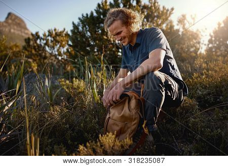Smiling Male Photographer Packing His Bag In Meadow