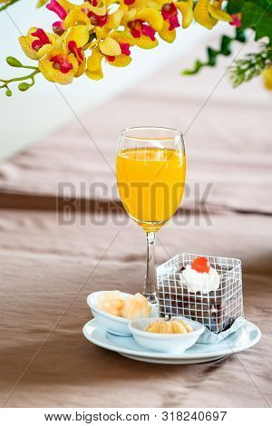 Orange Juice In Champagne Glass With Cake And Bagery Beside.