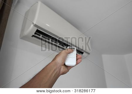 Mans Hand Using Remote Controler. Hand Holding Rc And Adjusting Temperature Of Air Conditioner Mount