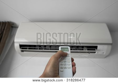 Mans Hand Using Remote Controler. Hand Holding Rc And Adjusting Temperature Of Air Conditioner Mount