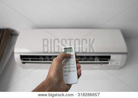 Mans Hand Using Remote Controler. Hand Holding Rc And Adjusting Temperature Of Air Conditioner Mount