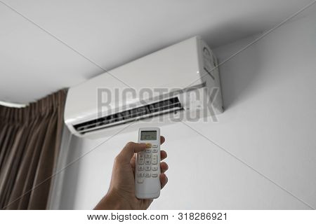 Mans Hand Using Remote Controler. Hand Holding Rc And Adjusting Temperature Of Air Conditioner Mount