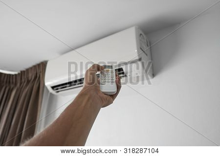 Mans Hand Using Remote Controler. Hand Holding Rc And Adjusting Temperature Of Air Conditioner Mount