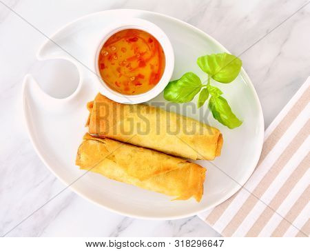 Hot Crispy Chinese Vegetable Spring Rolls With Sweet Chili Sauce And Basil Garnish.  On White Plate 
