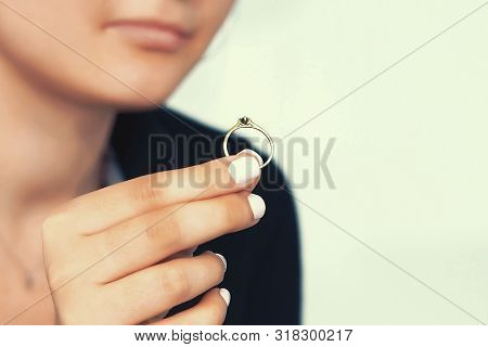 Close-up Of Hand Woman Holding Wedding Engagement Ring In Hands, Engaged Girl Doubts About Marriage 