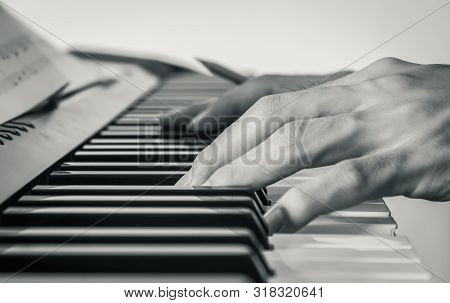 Hand Of Piano Player On White Keys And Black Keys Of Electric Piano With Piano Staff