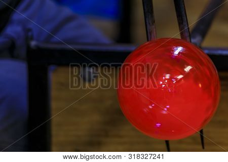 Glass Blower Shaping A Bubble Of Melted Glass On A Rod By Hand In The Manufacturing Process At A Gla