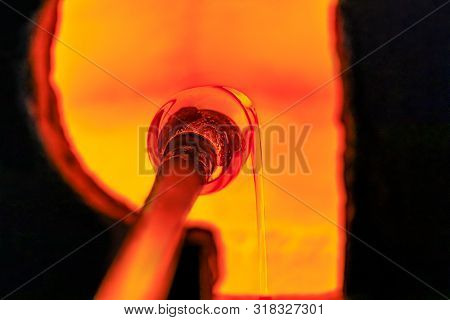 Glass Blower Manufacturing Process, Working On A Bubble Of Melted Glass On A Rod By Heating It Up By