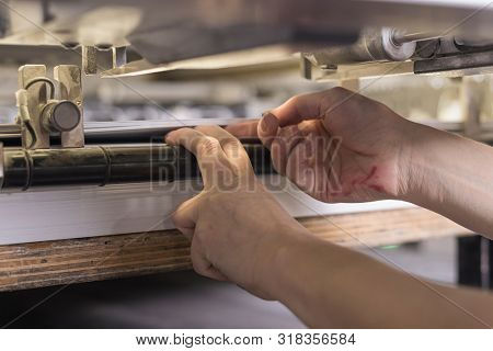 printing operator working on an offset printing maschine checking the final print