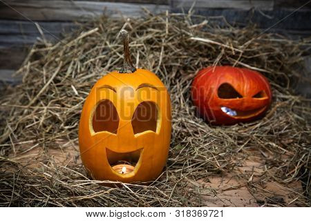 Red And Yellow Halloween Pumpkins Lie On The Hay Against The Background Of A Gray Stone Wall. Yellow