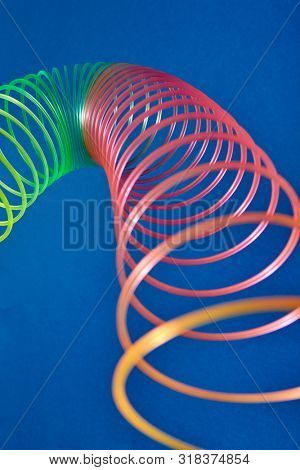 Flexible stretching multicolored slinky toy close up view with blurred foreground, place for text.