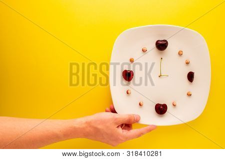 Hand Reaching For A Plate With Leftover Cherries Showing The Time.