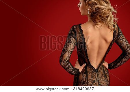 Back View Of Slim Young Female Wearing Black Lace Backless Dress And Holding Hands On Waist Against 