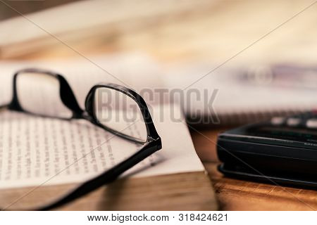 Books With Glasses Scattered On A Wooden Table. Background Concept For Exam Study, Hard Working And 