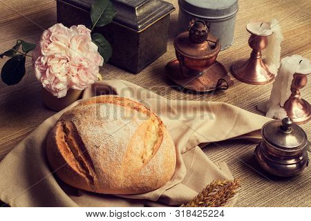 A Loaf Of Bread On A Wooden Table With Candless