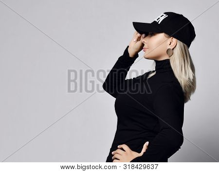 Sexy Curvy Blonde Woman In Black Stylish Turtleneck Sweater Holding The Visor Of Her Cap Pulling It 