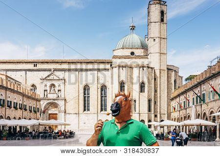 Horse Man Standing In The Middle Of The Historic Square Of Ascoli Piceno In Italy, Eating A Fried Ol