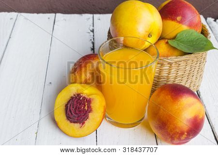 Delicious And Juicy Peach (nectarina) With Glass Of Juice On White Wooden Table.