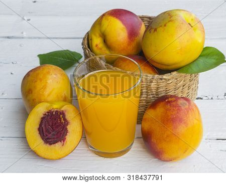 Delicious And Juicy Peach (nectarina) With Glass Of Juice On White Wooden Table.
