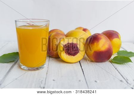 Delicious And Juicy Peach (nectarina) With Glass Of Juice On White Wooden Table.