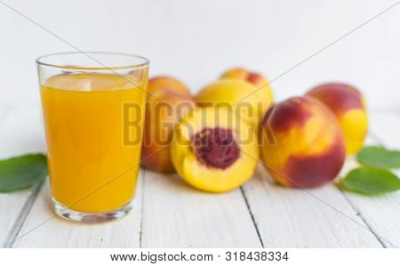 Delicious And Juicy Peach (nectarina) With Glass Of Juice On White Wooden Table.
