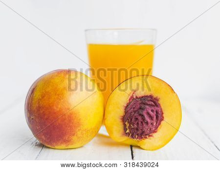 Delicious And Juicy Peach (nectarina) With Glass Of Juice On White Wooden Table.