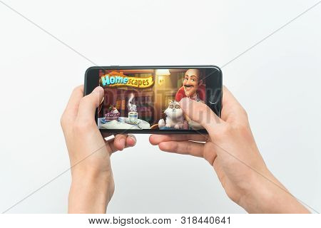 Samara, Russia -07, 29, 2019: A Young Guy Playing Homescapes Game On Iphone 8 Plus. Teenage Boy Hold
