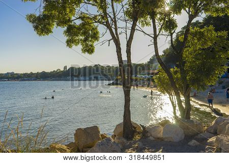 View Of The Black Sea From The Pier At Sunset. Through The Tree On The Stones You Can See The Suns R