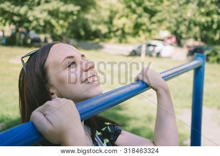 A Young Handsome Woman In Casual Clothes Is Doing Pull Up Exercise On Horizontal Bar. Fitness, Sport