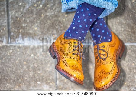 Crossed Mens Legs Wearing Brown Oxfords Semi Brogues Shoes. Posing Outdoors Against Stony Grunge Bac