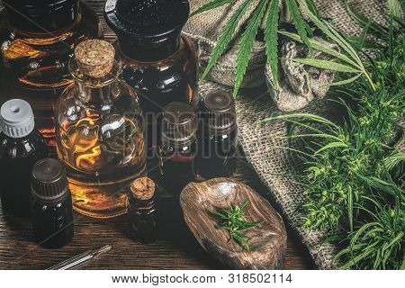 Cbd Oil Bottles And Green Plant Of Cannabis On A Wooden Background. Herbal Medicine.