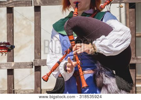 Woman In Medieval Clothes Playing On A Bagpipe