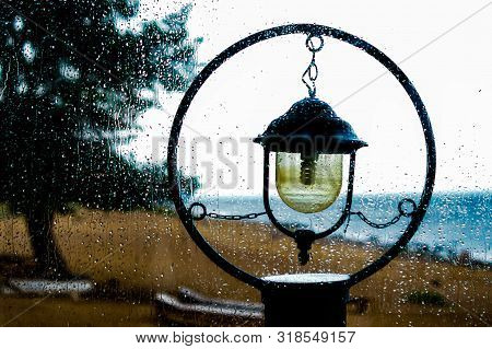 Melancholic Picture Of Vintage Streetlight In The Dull Rainy Day With A Sea And Pinetree Background 