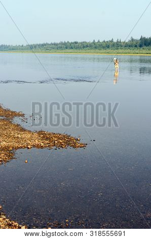 Yakut Girl-tourist Angler Fishing Spinning Reel Standing In Water With Rolled Up Pants On The Rocks,